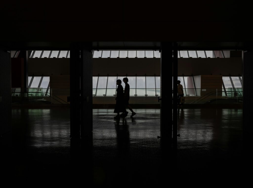 pexels-photo-17586141-17586141 Silhouette of people walking through a modern hallway with large windows in Shanghai, China.